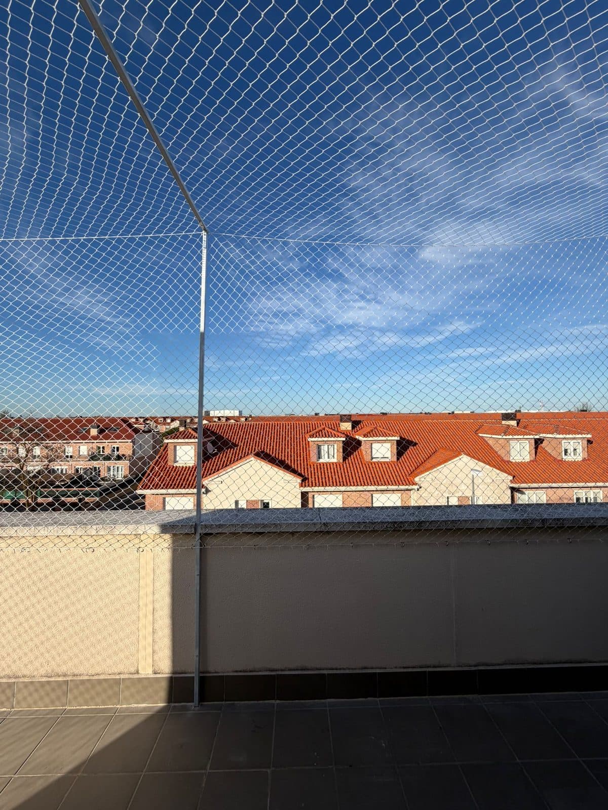 Terraza cerrada con red de protección bajo un cielo despejado